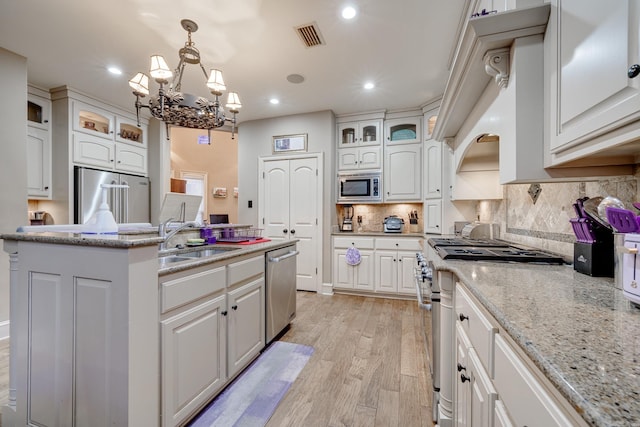 kitchen with sink, white cabinets, decorative light fixtures, and high end appliances