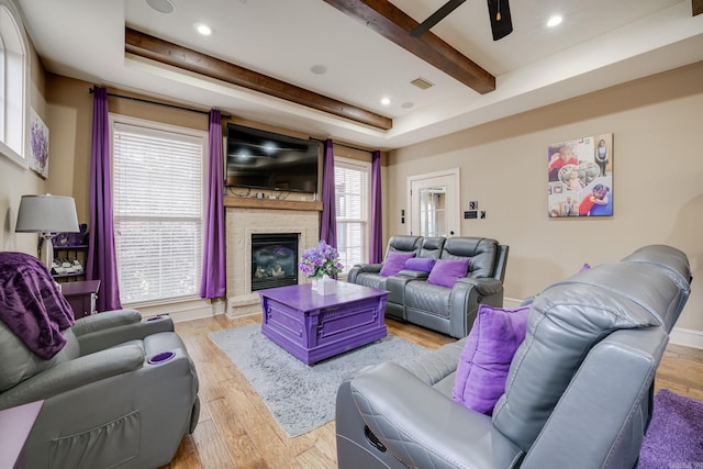 living room featuring a tray ceiling, ceiling fan, plenty of natural light, and light hardwood / wood-style floors