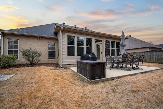 back house at dusk featuring a patio area and a yard