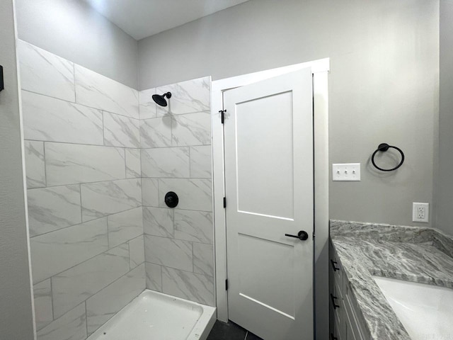 bathroom with tiled shower and vanity