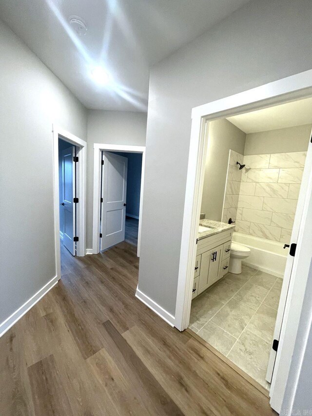 full bathroom with vanity, wood-type flooring, tiled shower / bath, and toilet