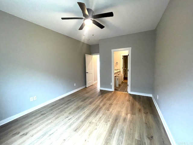 unfurnished bedroom featuring ensuite bath, wood-type flooring, and ceiling fan