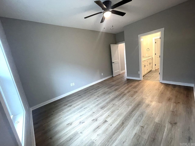 unfurnished bedroom featuring ceiling fan, ensuite bathroom, and light hardwood / wood-style flooring