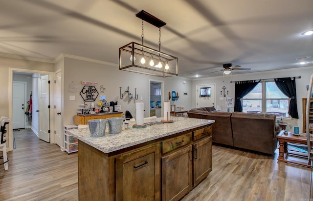 kitchen with pendant lighting, a center island, ceiling fan, and crown molding