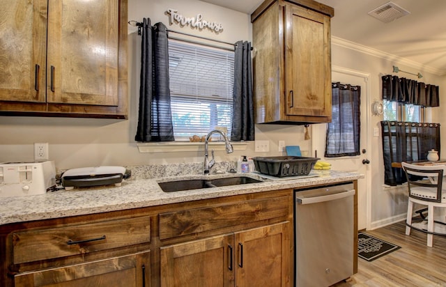 kitchen with light wood-type flooring, light stone counters, stainless steel dishwasher, ornamental molding, and sink