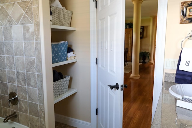 bathroom with hardwood / wood-style flooring, shower / tub combination, and ornate columns