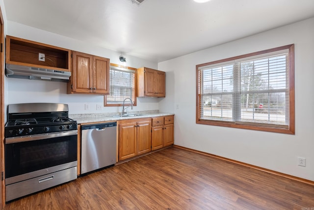 kitchen featuring light stone counters, sink, dark wood-type flooring, and stainless steel appliances