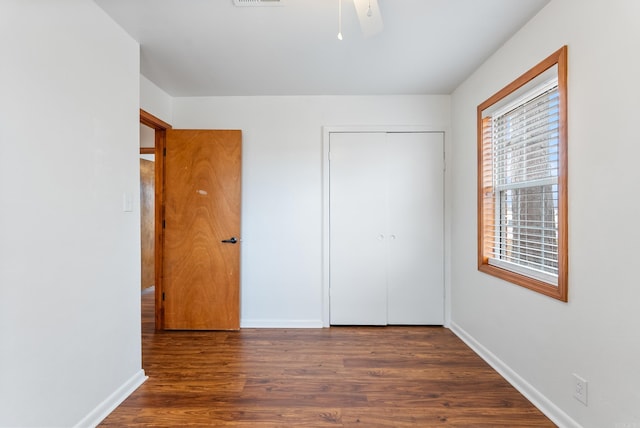 unfurnished bedroom featuring ceiling fan, dark hardwood / wood-style flooring, and a closet