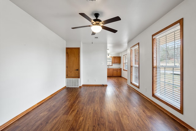 unfurnished living room with dark hardwood / wood-style flooring, sink, and ceiling fan