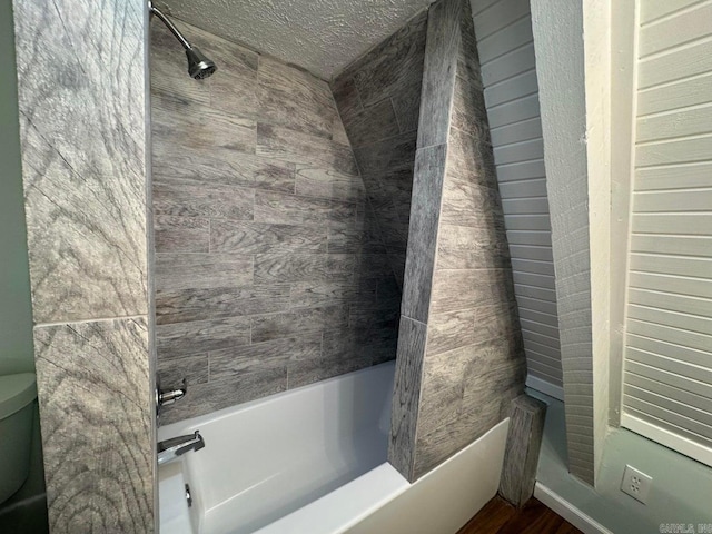 bathroom with hardwood / wood-style floors, tiled shower / bath combo, and toilet