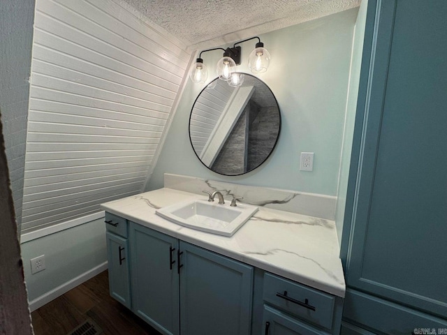 bathroom featuring hardwood / wood-style flooring, vanity, and a textured ceiling