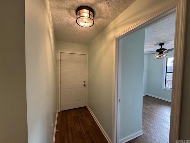 corridor featuring a textured ceiling and dark wood-type flooring