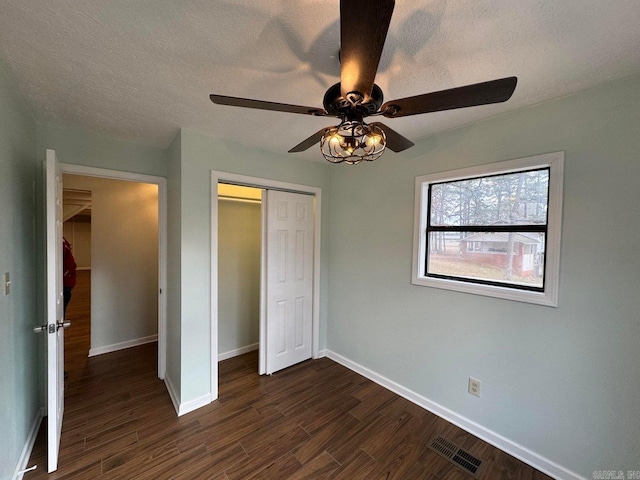 unfurnished bedroom with a closet, ceiling fan, and dark wood-type flooring