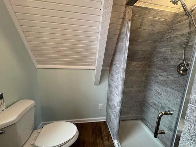 bathroom with toilet, wood-type flooring, and tiled shower