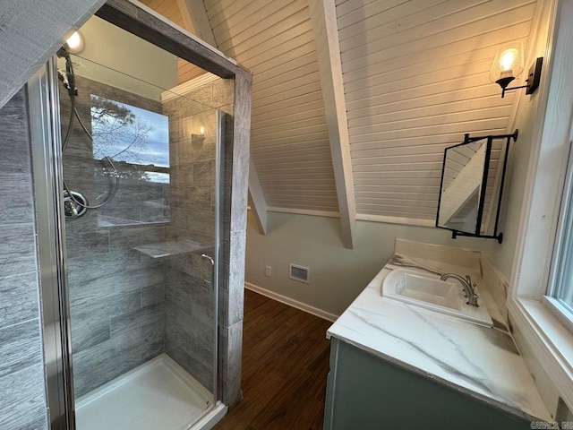 bathroom featuring hardwood / wood-style flooring, vanity, lofted ceiling with beams, and a shower with door