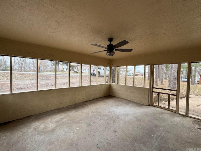 unfurnished sunroom featuring ceiling fan and a healthy amount of sunlight