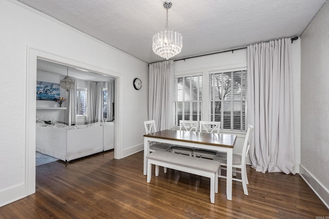 dining room featuring a notable chandelier, a healthy amount of sunlight, a textured ceiling, and dark wood-type flooring