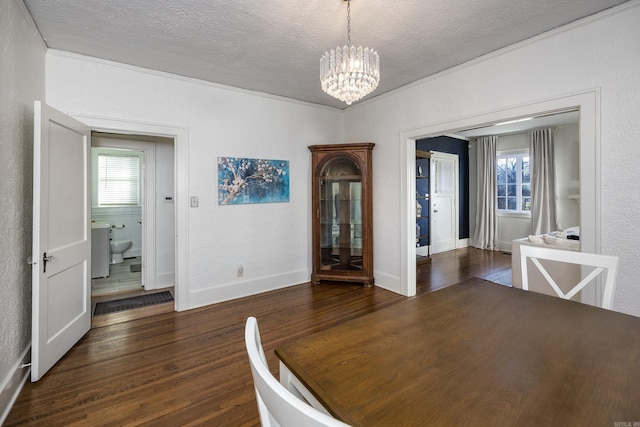 unfurnished dining area with a textured ceiling, an inviting chandelier, dark wood-type flooring, and crown molding