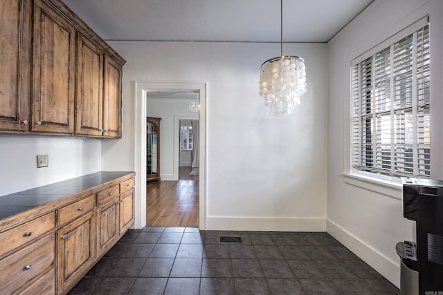 kitchen featuring dark tile patterned floors, hanging light fixtures, and a notable chandelier