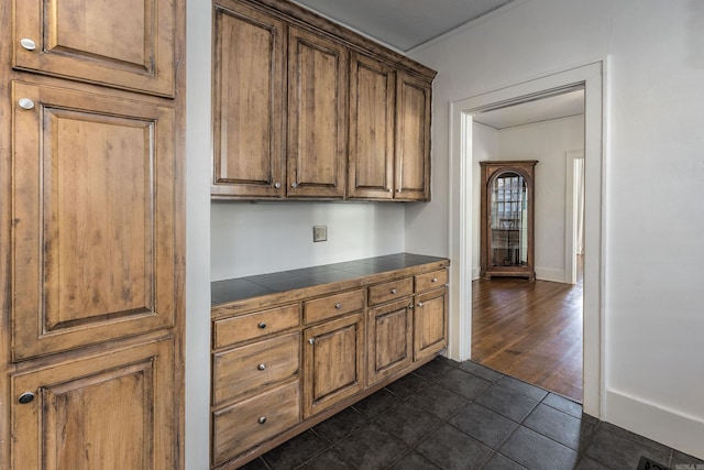 kitchen with dark tile patterned floors and crown molding