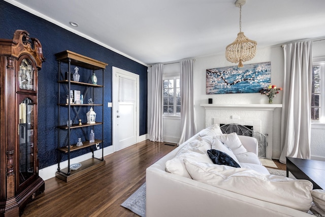 bedroom with an inviting chandelier, dark hardwood / wood-style flooring, crown molding, and a brick fireplace