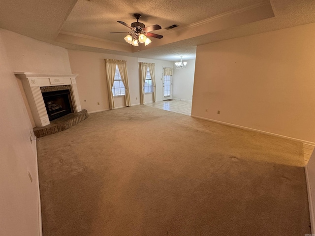 unfurnished living room featuring a raised ceiling, a textured ceiling, a fireplace, carpet, and ceiling fan with notable chandelier