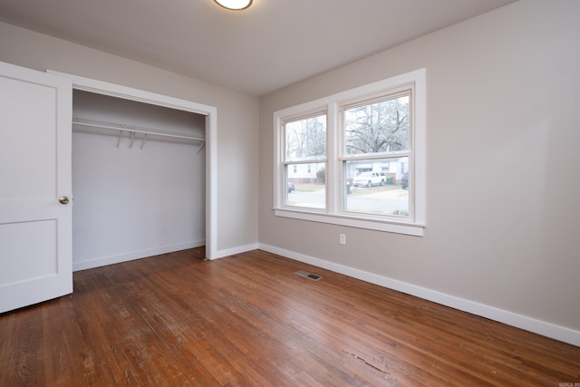 unfurnished bedroom with dark hardwood / wood-style floors and a closet