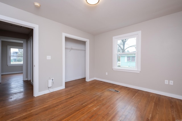 unfurnished bedroom featuring a closet, multiple windows, and dark wood-type flooring