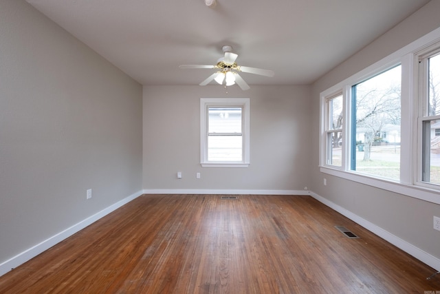 empty room with ceiling fan, dark hardwood / wood-style flooring, and a healthy amount of sunlight