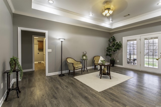 living area with a raised ceiling, ceiling fan, dark hardwood / wood-style flooring, and ornamental molding