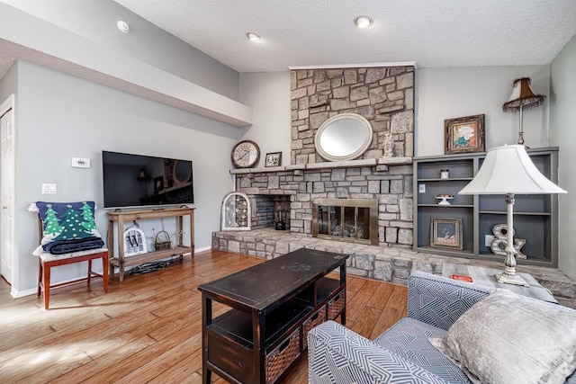 living room featuring a fireplace, a textured ceiling, vaulted ceiling, and light hardwood / wood-style flooring