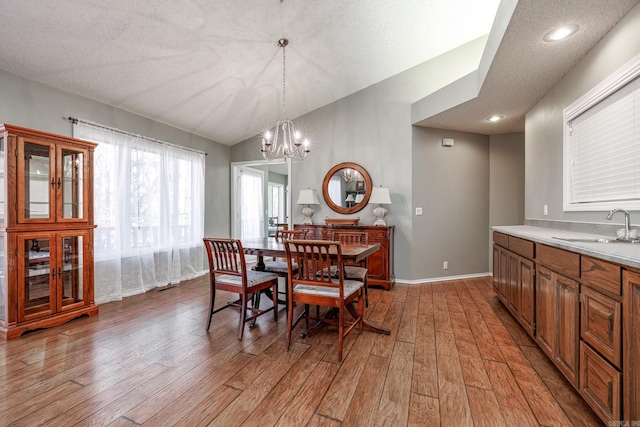 dining space with sink, hardwood / wood-style floors, an inviting chandelier, and a textured ceiling