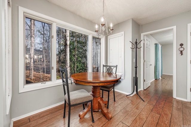 dining room featuring a textured ceiling, a notable chandelier, and hardwood / wood-style flooring