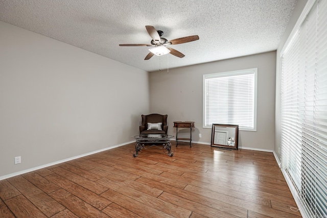 living area featuring a textured ceiling, hardwood / wood-style floors, and ceiling fan