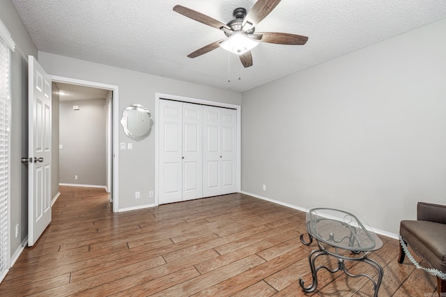 unfurnished room featuring light hardwood / wood-style floors, ceiling fan, and a textured ceiling