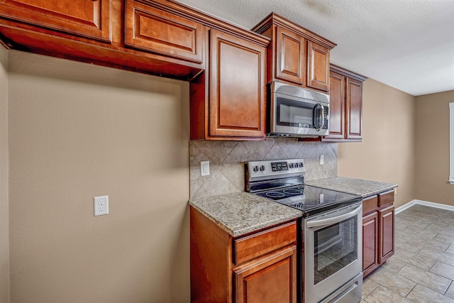 kitchen featuring appliances with stainless steel finishes, backsplash, and light stone counters