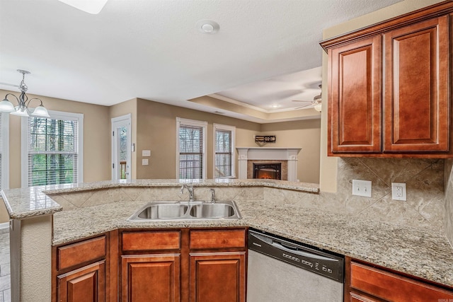 kitchen featuring dishwasher, sink, kitchen peninsula, a tray ceiling, and ceiling fan with notable chandelier