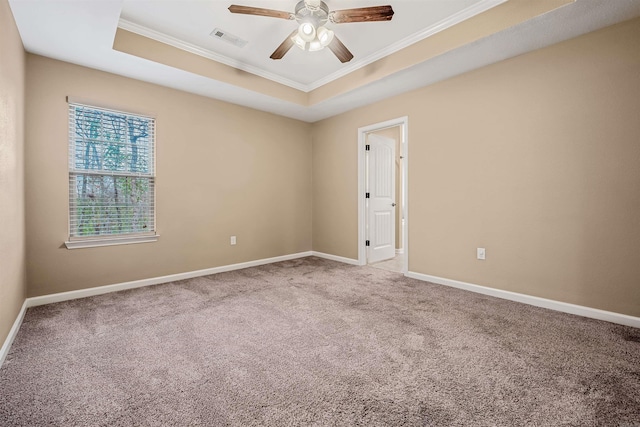 empty room with carpet floors, a raised ceiling, and ornamental molding