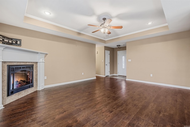 unfurnished living room with dark hardwood / wood-style flooring, a raised ceiling, and a tiled fireplace