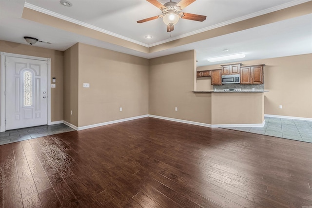 unfurnished living room with ceiling fan, wood-type flooring, ornamental molding, and a tray ceiling