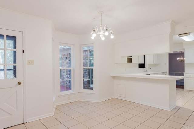 kitchen with kitchen peninsula, crown molding, a notable chandelier, white cabinets, and hanging light fixtures