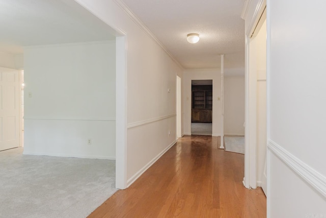 hallway with carpet flooring, a textured ceiling, and crown molding