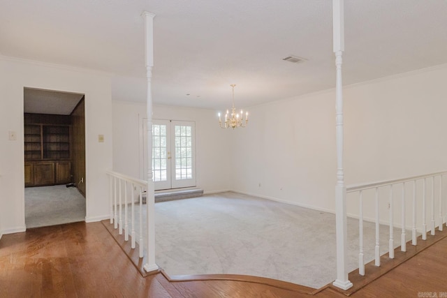 empty room featuring crown molding, french doors, hardwood / wood-style flooring, and a notable chandelier