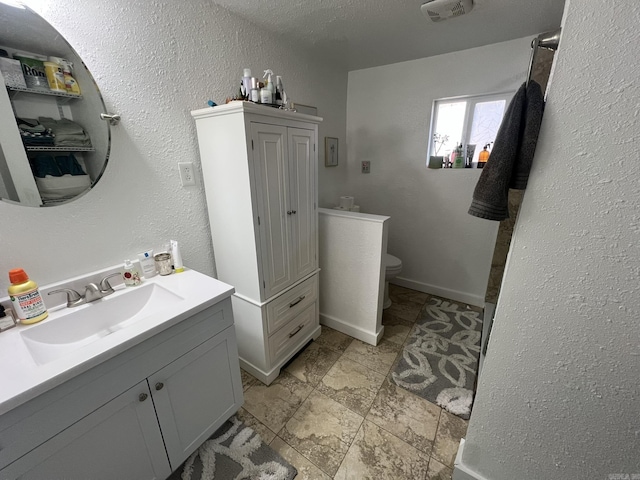 bathroom featuring vanity, toilet, and a textured ceiling