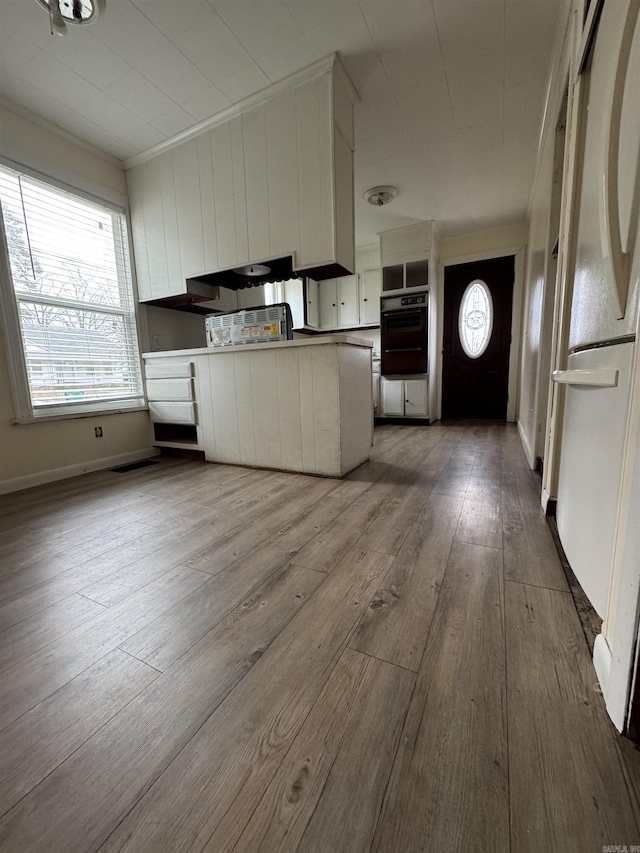 kitchen featuring white fridge, white cabinetry, crown molding, and light hardwood / wood-style flooring