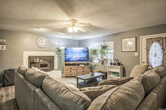 living room with hardwood / wood-style floors, ceiling fan, and a textured ceiling