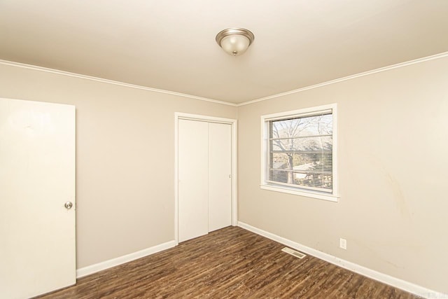 unfurnished bedroom with crown molding, a closet, and dark hardwood / wood-style floors