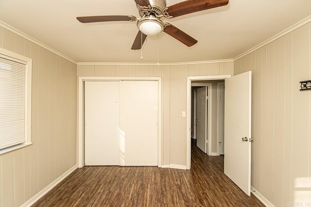 unfurnished bedroom with ceiling fan, a closet, dark wood-type flooring, and ornamental molding