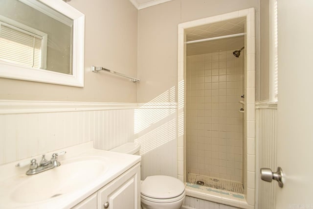 bathroom featuring toilet, tiled shower, wooden walls, vanity, and ornamental molding