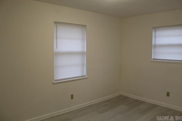 spare room featuring a textured ceiling and light hardwood / wood-style flooring